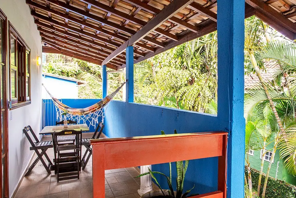 Varanda do Apartamento com rede, mesa e jardim