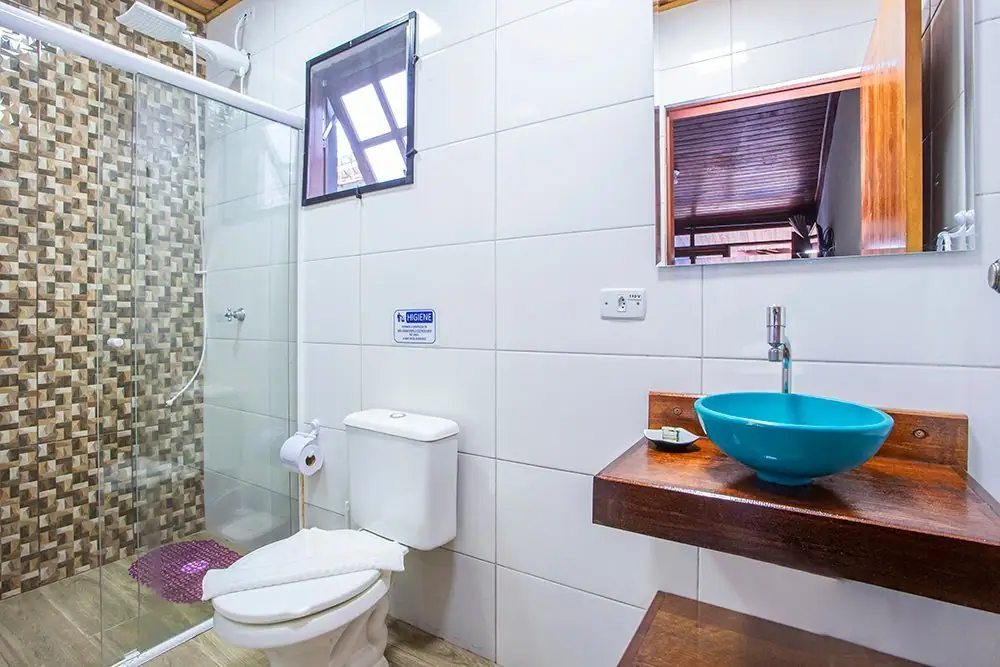 Banheiro da Suíte Standard com box de vidro e pia de cuba azul